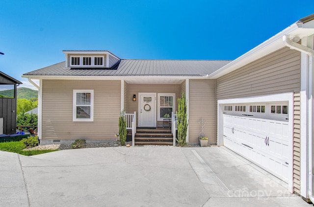view of front of house with an attached garage, crawl space, metal roof, a porch, and driveway
