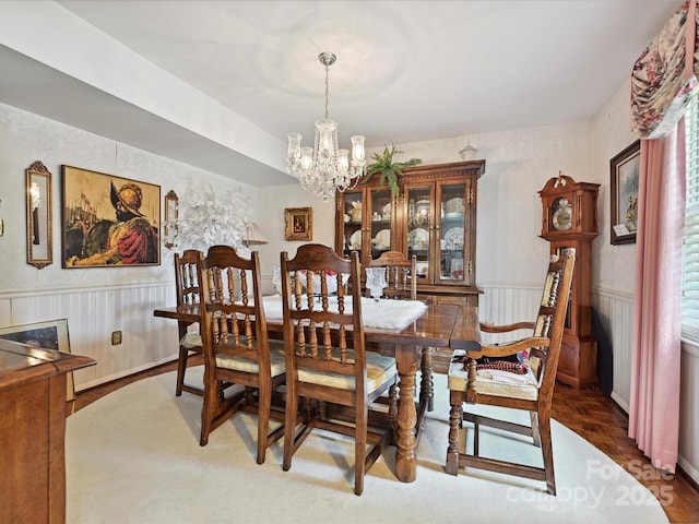 dining space featuring an inviting chandelier and a wainscoted wall