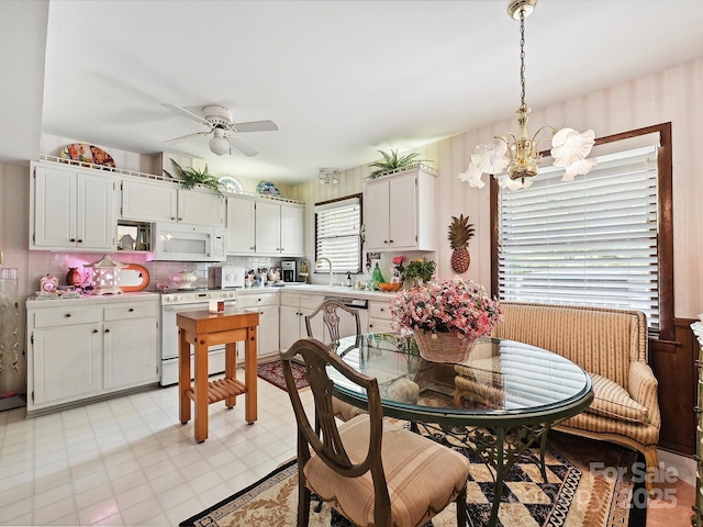 dining area with light floors, wallpapered walls, and ceiling fan with notable chandelier