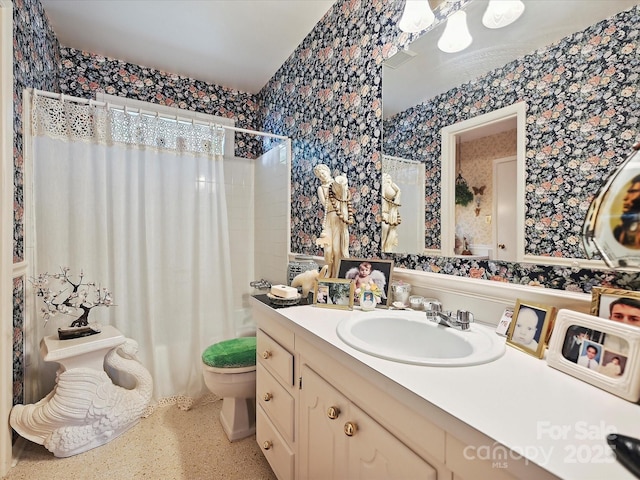 bathroom with toilet, a shower with curtain, vanity, speckled floor, and wallpapered walls