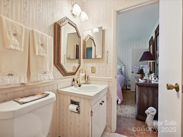 ensuite bathroom with wallpapered walls, toilet, connected bathroom, and vanity