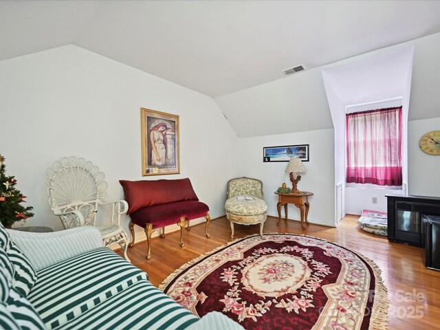 sitting room with visible vents, wood finished floors, and lofted ceiling