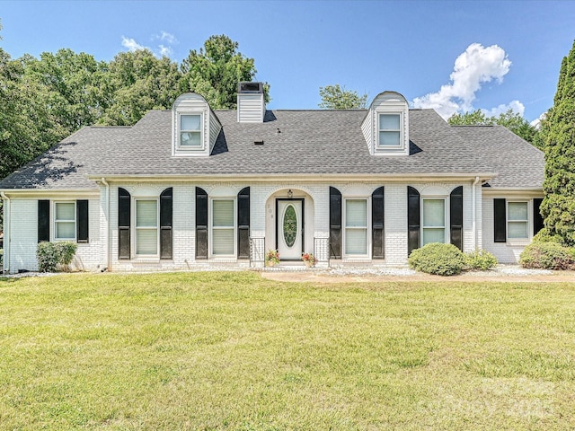 cape cod-style house with roof with shingles, brick siding, and a front lawn