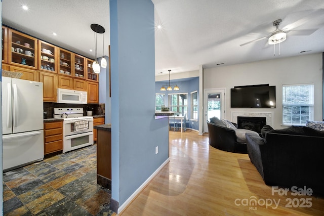 kitchen with white appliances, baseboards, a premium fireplace, a ceiling fan, and glass insert cabinets