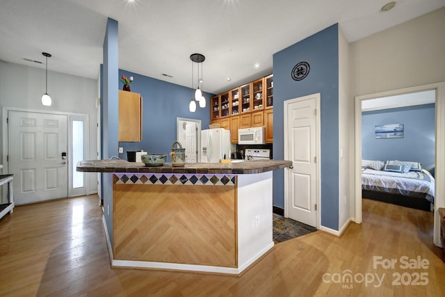 kitchen with white appliances, wood finished floors, a peninsula, decorative light fixtures, and baseboards