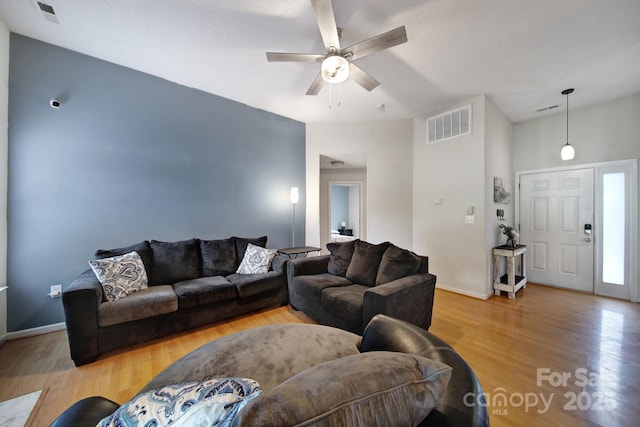 living area with light wood-style floors, ceiling fan, and baseboards