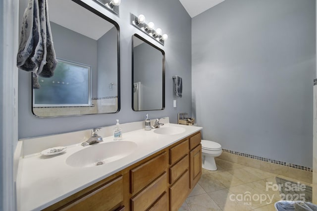 bathroom with double vanity, toilet, tile patterned flooring, and baseboards