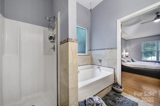 ensuite bathroom with a shower stall, a garden tub, lofted ceiling, and wood finished floors