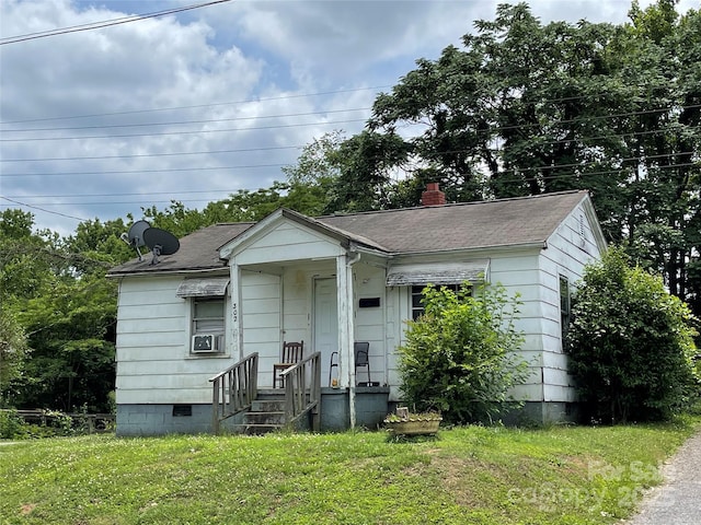 bungalow-style house featuring crawl space, a chimney, roof with shingles, cooling unit, and a front lawn