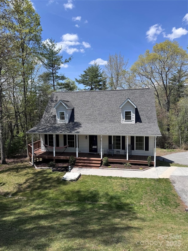 cape cod-style house with a shingled roof, covered porch, and a front yard