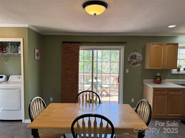 dining area featuring dark tile patterned floors, a textured ceiling, a healthy amount of sunlight, and washing machine and clothes dryer