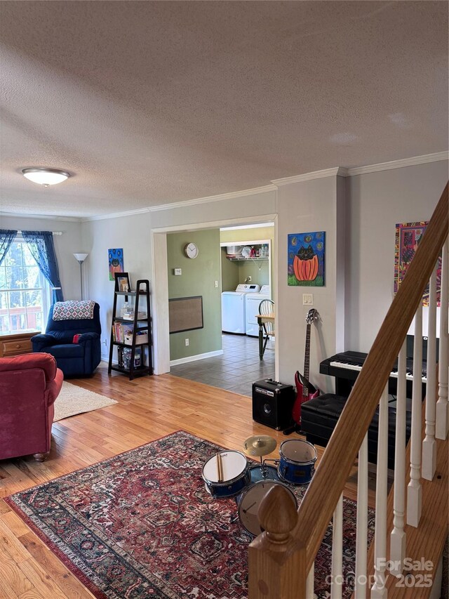 living room featuring crown molding, wood finished floors, a textured ceiling, and washing machine and clothes dryer