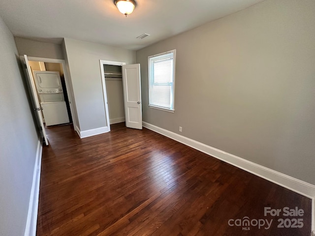 unfurnished bedroom with baseboards, dark wood finished floors, visible vents, and a closet