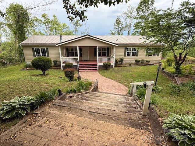 single story home with a porch, a front lawn, and metal roof