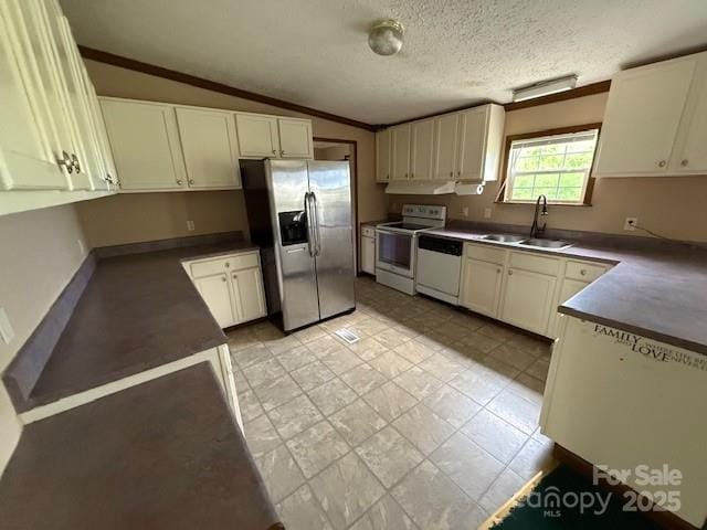 kitchen featuring dark countertops, white appliances, range hood, a sink, and vaulted ceiling