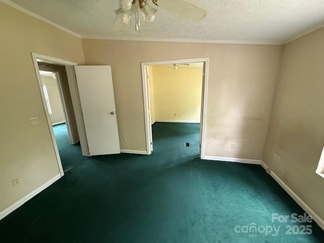 carpeted spare room with crown molding, a textured ceiling, and baseboards
