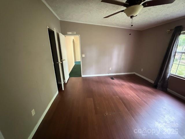 spare room featuring visible vents, wood finished floors, baseboards, a textured ceiling, and a ceiling fan
