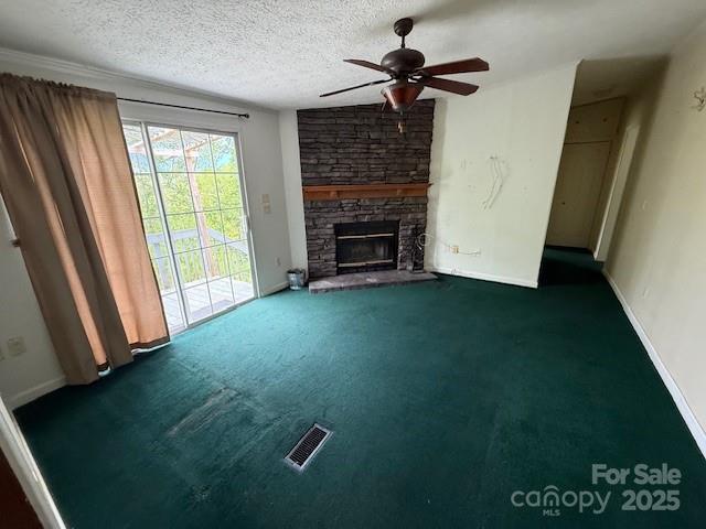 unfurnished living room with visible vents, carpet flooring, baseboards, a stone fireplace, and a ceiling fan