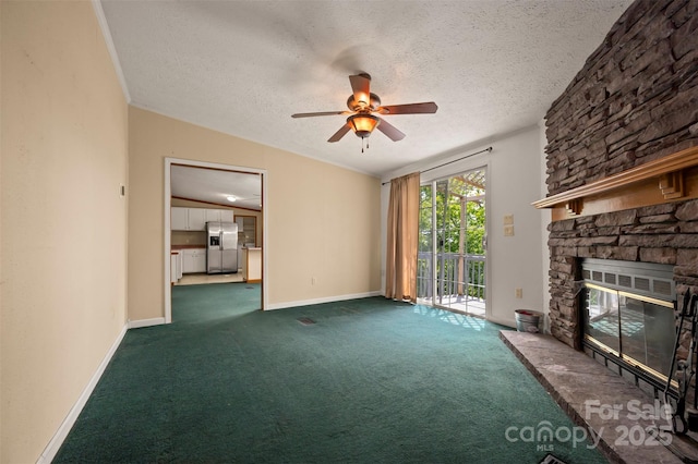 257 River Crest Dr, Flat Rock, NC 28731 - unfurnished living room with a ceiling fan, a textured ceiling, baseboards, a stone fireplace, and dark colored carpet