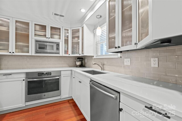 kitchen featuring visible vents, wood finished floors, a sink, white cabinets, and stainless steel appliances