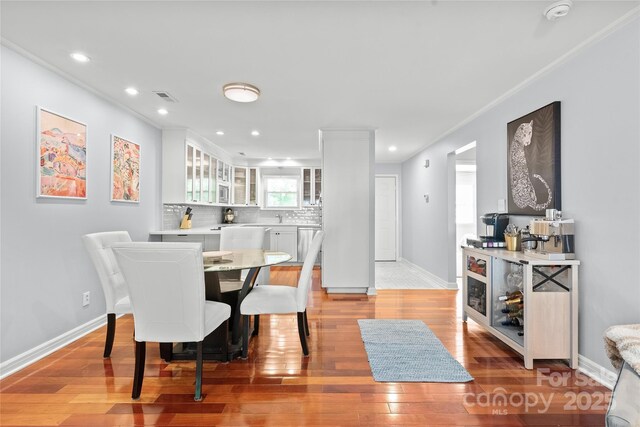 dining room with visible vents, crown molding, light wood-style floors, baseboards, and recessed lighting