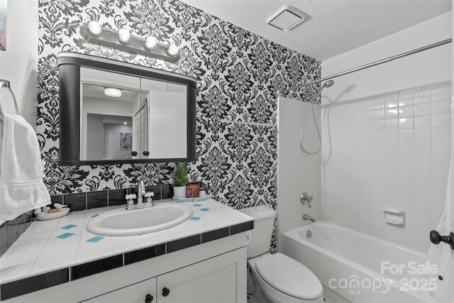 bathroom featuring vanity, shower / bath combination, toilet, and wallpapered walls