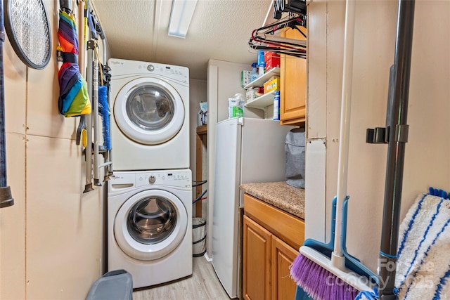743 Dream Ln, Salisbury, NC 28146 - clothes washing area featuring cabinet space, a textured ceiling, stacked washing maching and dryer, and light wood-style floors