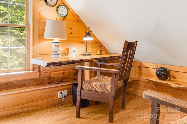 living area featuring wood finished floors, healthy amount of natural light, and wooden walls