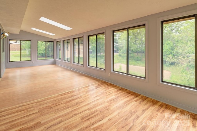 unfurnished sunroom featuring vaulted ceiling, wood finished floors, a skylight, baseboards, and a deck