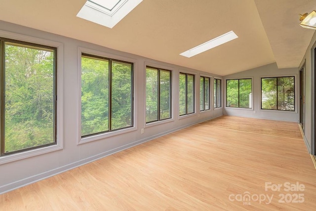 unfurnished sunroom featuring a skylight, healthy amount of natural light, wood finished floors, and vaulted ceiling