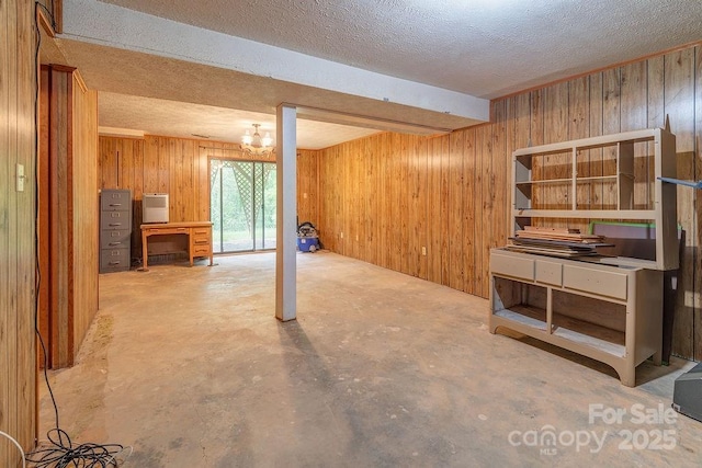 basement with wooden walls, a textured ceiling, and a chandelier