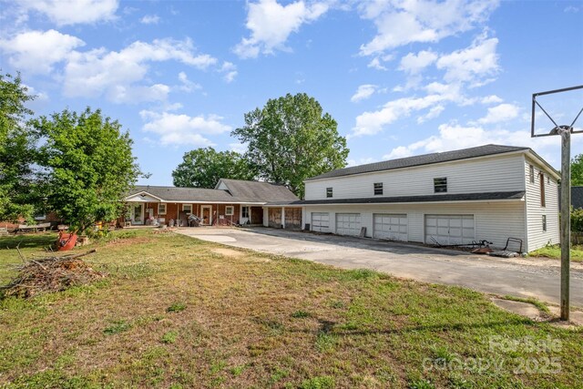 back of property with covered porch, a lawn, an attached garage, and aphalt driveway