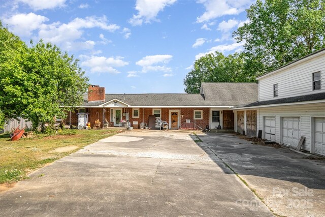 view of front facade with concrete driveway, brick siding, a chimney, and a porch