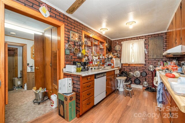 kitchen with white dishwasher, light countertops, light wood-style floors, and under cabinet range hood
