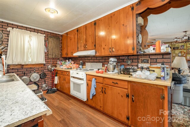 kitchen with white range with electric cooktop, brown cabinets, light wood-type flooring, light countertops, and under cabinet range hood