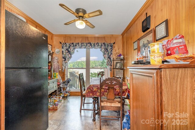 dining room featuring crown molding, wood walls, and ceiling fan