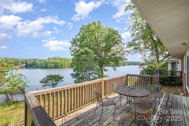 wooden deck with outdoor dining space and a water view