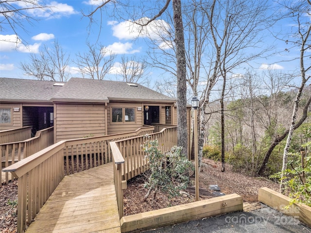 rear view of property featuring roof with shingles and a wooden deck