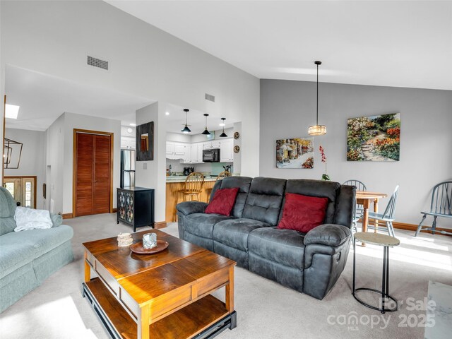 living room with baseboards, light carpet, vaulted ceiling, and visible vents