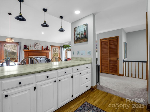 kitchen featuring pendant lighting, wood finished floors, light stone counters, white cabinets, and recessed lighting