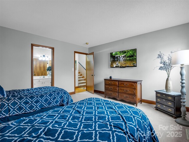 bedroom with a sink, baseboards, connected bathroom, and light colored carpet