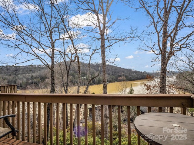 wooden terrace featuring a view of trees and a water and mountain view