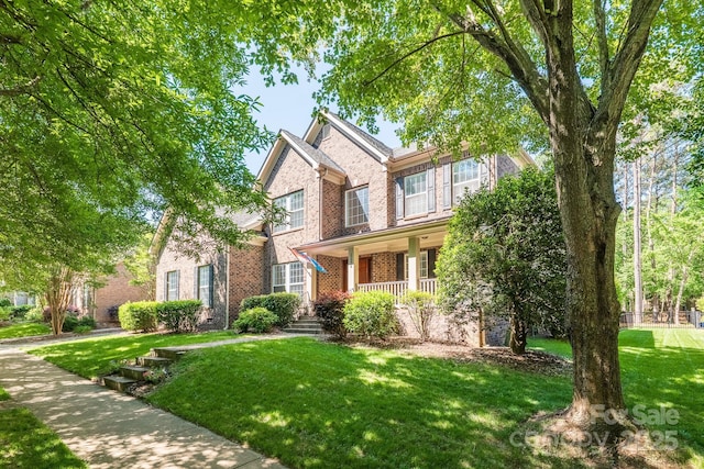 view of front of property with brick siding, a front lawn, and covered porch