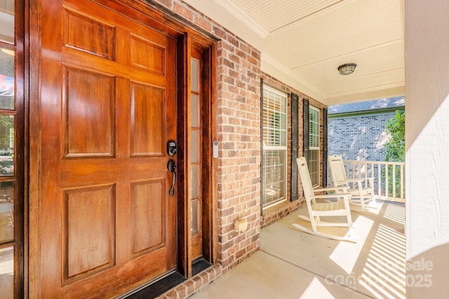 property entrance featuring brick siding and covered porch