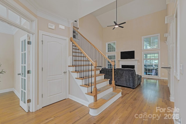 staircase featuring ceiling fan, wood finished floors, and a high ceiling