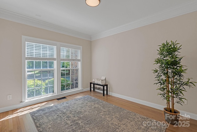 sitting room featuring baseboards, visible vents, ornamental molding, and wood finished floors