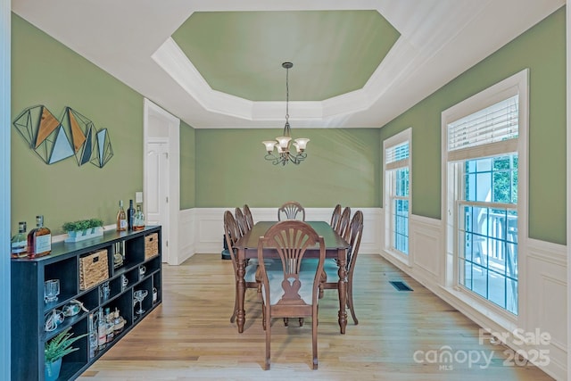 dining area with a chandelier, a wainscoted wall, visible vents, and a decorative wall