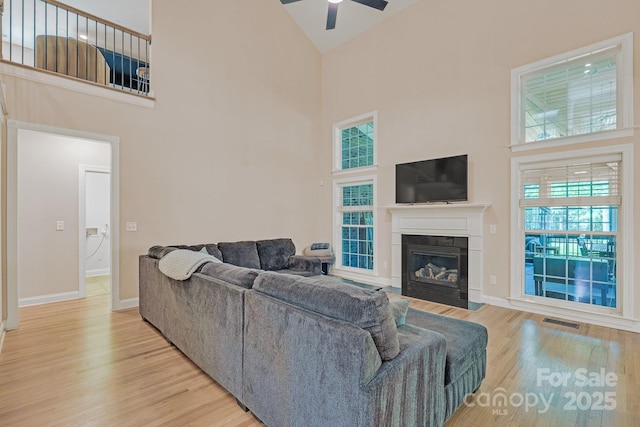 living area with a ceiling fan, high vaulted ceiling, visible vents, and light wood-style flooring