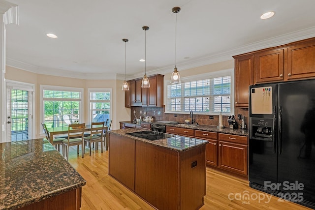 kitchen with light wood-type flooring, a sink, black appliances, and a center island