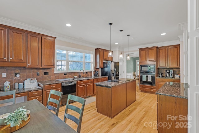kitchen featuring a sink, a center island, light wood-type flooring, ornamental molding, and black appliances